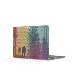 Puede incluir: Funda para portátil con la silueta de un Bigfoot caminando por un bosque. El diseño tiene una estética vintage con un fondo degradado colorido y texto manuscrito. La funda está diseñada para un portátil.