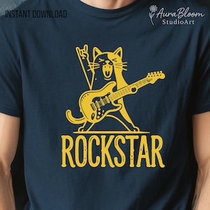 May include: Navy blue t-shirt featuring a yellow cartoon cat playing a guitar with a rock and roll hand gesture. The word "ROCKSTAR" is printed in yellow below the cat. The shirt has the text "INSTANT DOWNLOAD" in the upper left corner.