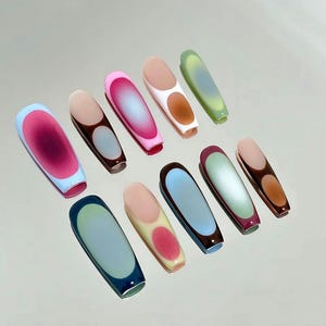 May include: A set of ten long, coffin-shaped press-on nails featuring various gradient color combinations. Each nail displays a smooth, glossy finish with a central oval or rounded rectangular color transition, including shades of pink, blue, green, and brown.