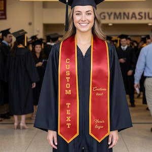May include: A smiling graduate in a black cap and gown, wearing a red and gold custom sash. The sash has the words "CUSTOM TEXT" and "Your logo" printed on it. The background includes a banner that says "WELCOME GRADUATES".
