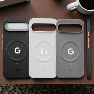 Puede incluir: Tres fundas para teléfono en negro, blanco y gris, cada una con un diseño circular con la letra "G" y un recorte rectangular. Un teléfono negro a juego está a la derecha. Las fundas tienen un aspecto texturizado.