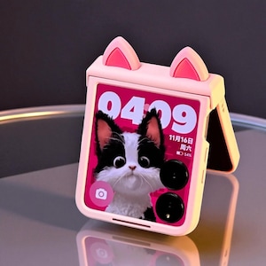 May include: A pink flip phone case with cat ear accents. The phone screen displays a black and white cat image with the time 04:09 and the date November 16th. The case has a camera icon and a battery indicator.