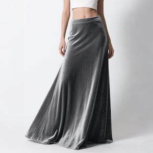 May include: A white sleeveless crop top paired with a long, flowing gray velvet skirt. The skirt has a high waist and a slight A-line shape. The outfit is elegant and suitable for formal occasions.