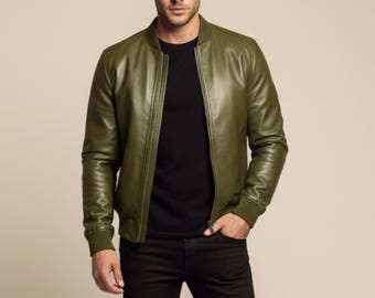 May include: Olive green leather bomber jacket with a ribbed collar and cuffs. The jacket has a front zipper closure and is worn over a black crew neck shirt and black pants. A stylish outerwear piece.