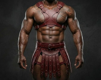 Pode incluir: Um conjunto de arnês e saia de couro bordô. O arnês apresenta várias tiras e rebites, enquanto a saia tem um design plissado com tiras correspondentes. O conjunto é projetado com um tema gladiador.