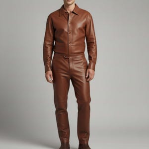 Puede incluir: Imagen de cuerpo entero de un atuendo de cuero marr&oacute;n. El conjunto consta de una camisa abotonada y pantalones a juego. La camisa tiene cuello y mangas largas. Los pantalones son de corte recto. El atuendo es de cuero liso y brillante.