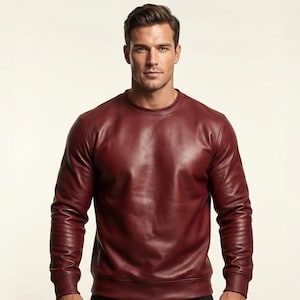 Könnte beinhalten: Ein weinrotes Leder-Sweatshirt mit Rundhalsausschnitt und langen Ärmeln. Das Kleidungsstück hat ein glattes, poliertes Aussehen und ein klassisches Design. Das Sweatshirt ist einfarbig und scheint aus hochwertigem Leder zu sein.