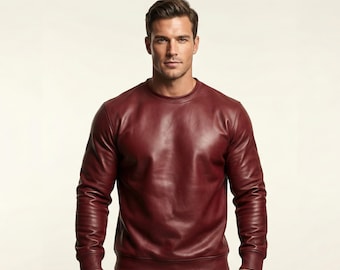 May include: A burgundy leather sweatshirt with a crew neck and long sleeves. The garment has a smooth, polished appearance and a classic design. The sweatshirt is a solid color and appears to be made of high-quality leather.