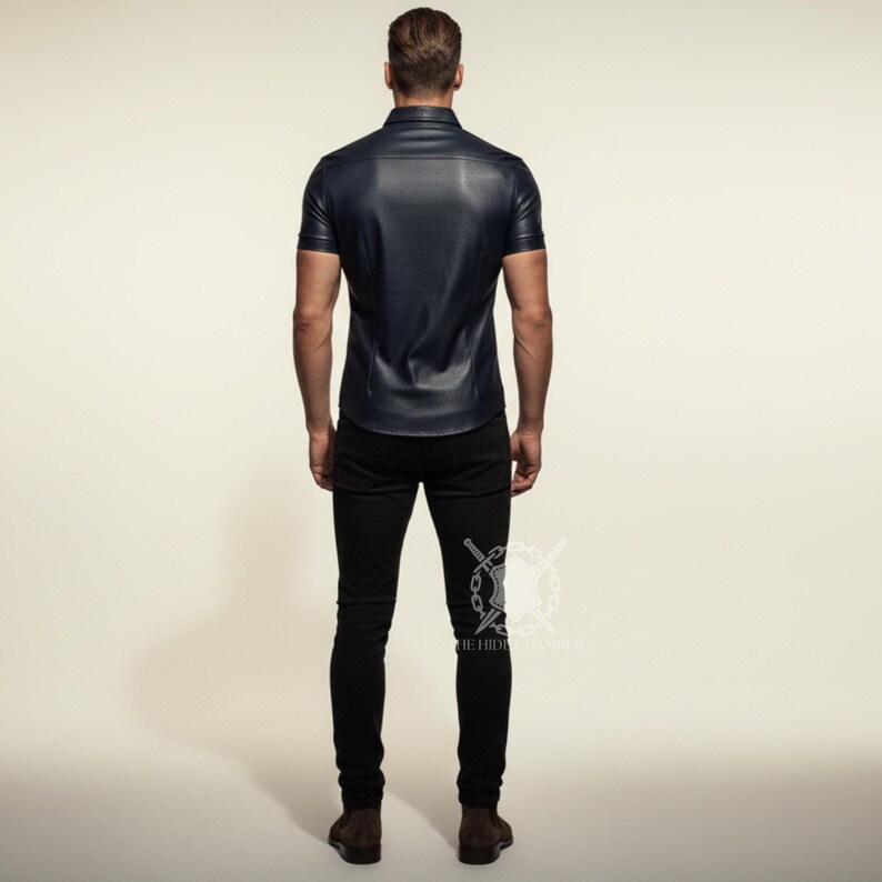 Pu&ograve; includere: Una camicia di pelle blu navy a maniche corte con colletto button-down. La camicia &egrave; abbinata a jeans skinny neri e scarpe marroni. La persona &egrave; vista da dietro.