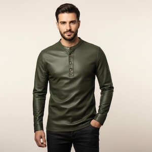 Op de afbeelding: Olijfgroen shirt met lange mouwen, een opstaande kraag en een knoopsluiting met drie knopen. Het shirt is gemaakt van een glad, leerachtig materiaal. Het model draagt een donkere jeans.