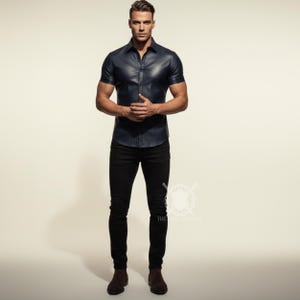 Pu&ograve; includere: Una camicia di pelle blu navy a maniche corte con bottoni. La camicia &egrave; abbinata a pantaloni neri e stivali marroni. L'immagine &egrave; ambientata su uno sfondo neutro.