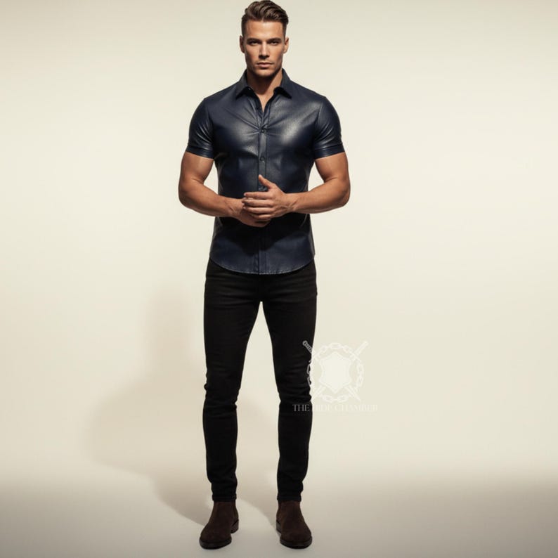Pu&ograve; includere: Una camicia di pelle blu navy a maniche corte con bottoni. La camicia &egrave; abbinata a pantaloni neri e stivali marroni. L'immagine &egrave; ambientata su uno sfondo neutro.