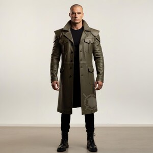 May include: Olive green leather coat with a classic trench coat design. Features a notched collar, shoulder epaulets, multiple pockets, and a button-down front. The coat is knee-length and worn with black pants and boots.