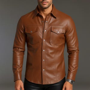 Può includere: Una camicia di pelle marrone con due tasche sul petto e bottoni argentati. La camicia a maniche lunghe ha un colletto classico ed è abbottonata. La pelle appare liscia e ha una leggera lucentezza.