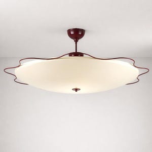 May include: A ceiling light fitting featuring a large, circular, off-white frosted glass shade. The shade is surrounded by a dark red, wavy metal frame. A matching dark red metal stem connects the light to a circular ceiling mount canopy.