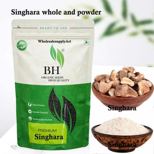 May include: A packet of "Singhara" whole and powder, with text that reads "READY TO USE" and "PREMIUM". The packet is white and green with a leaf design. Two wooden bowls contain the whole and powdered form of the product.