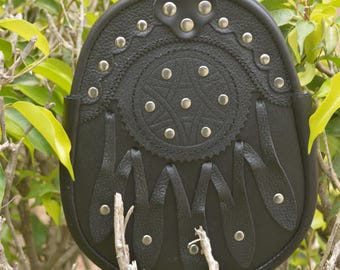May include: Black leather sporran with a decorative circular design and silver-tone studs. The sporran features a flap closure and hanging leather tassels. It is designed to be worn with traditional Scottish attire.