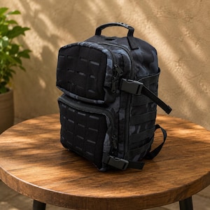 May include: A black and dark grey camouflage tactical backpack featuring two front zipped compartments with laser-cut MOLLE webbing panels, a top carry handle, side compression straps with plastic buckles, and multiple side attachment points.