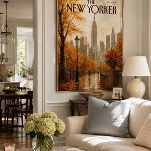 May include: A framed wall art print of a New Yorker magazine cover featuring an autumn scene in New York City with the Empire State Building, golden trees, a street lamp, and a wet path, all rendered in warm orange and brown tones.