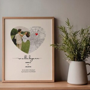 May include: Framed print featuring a heart-shaped puzzle design with a couple's photo and a map. The print includes the text "Wo alles begann" and names, with a red heart marking a location.