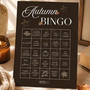 Könnte beinhalten: Eine schwarze, rechteckige Herbst-Bingo-Spielkarte mit weißem Text und Strichzeichnungen. Das Raster enthält fünfundzwanzig Quadrate mit saisonalen Aktivitäten wie Kürbiskuchen backen, ein Buch lesen und einen Pullover stricken. Der Titel lautet Autumn Bingo.