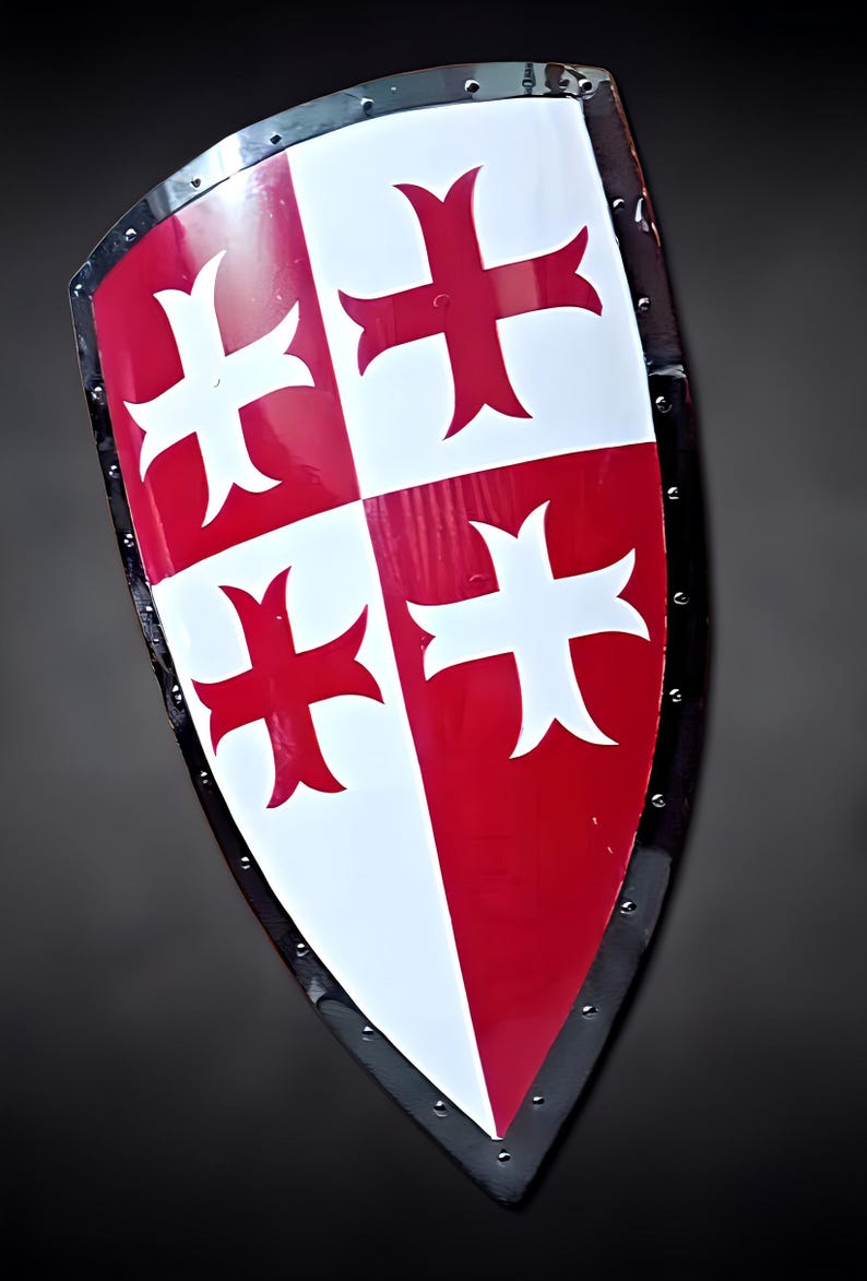 May include: A medieval-style shield with a red and white cross design. The shield is divided into four sections, with alternating red and white quadrants. The edges are trimmed with a black metal band and rivets.