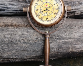 May include: Antique brass-colored desk clock with Roman numerals on the face. The clock has a stand and a decorative base. The clock face has the words "White Star Line" and "Titanic".