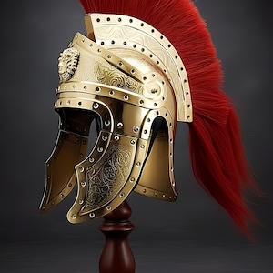 Op de afbeelding: Een goudkleurige Romeinse helm met een rode pluim, tentoongesteld op een houten standaard. De helm heeft ingewikkelde reliëfontwerpen en een leeuwenkopembleem. Het ontwerp van de helm omvat kinbeschermers en een gebogen kam.