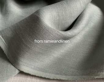 Könnte beinhalten: Nahaufnahme eines weichen, salbeigrünen Stoffes mit einer dezenten Textur. Der Stoff ist gefaltet und die Kante ist sichtbar.