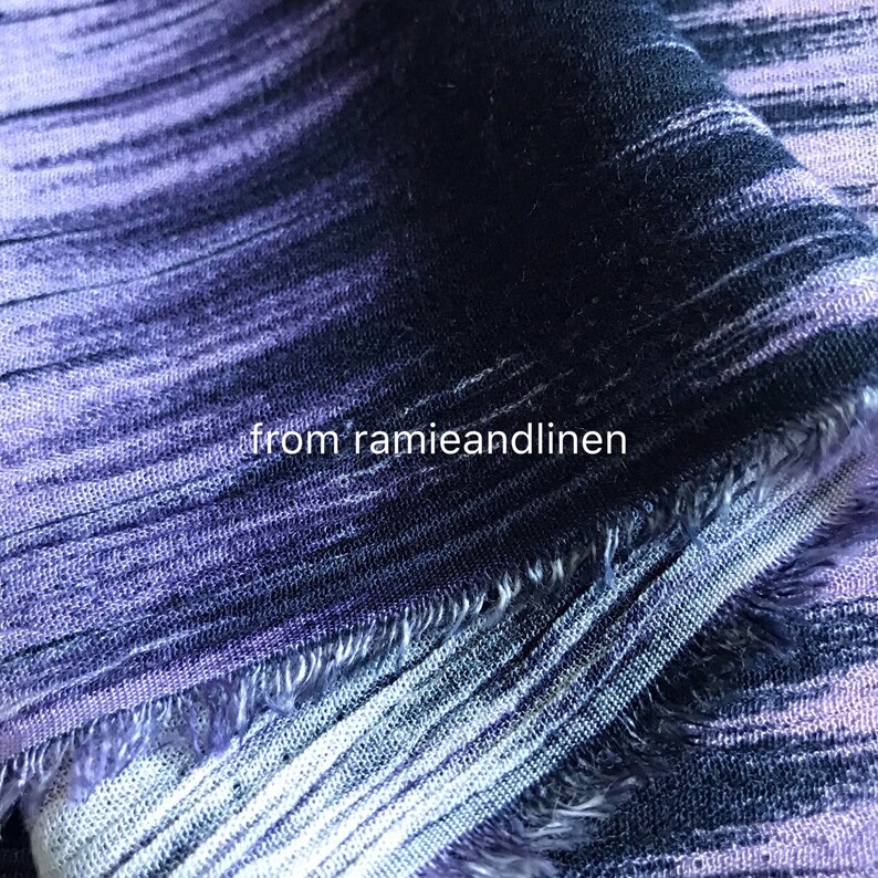 Puede incluir: Primer plano de una tela a rayas de color morado y negro con un borde deshilachado. La tela tiene un brillo sutil y una textura suave. "from ramieandlinen" est&aacute; impreso en la tela.