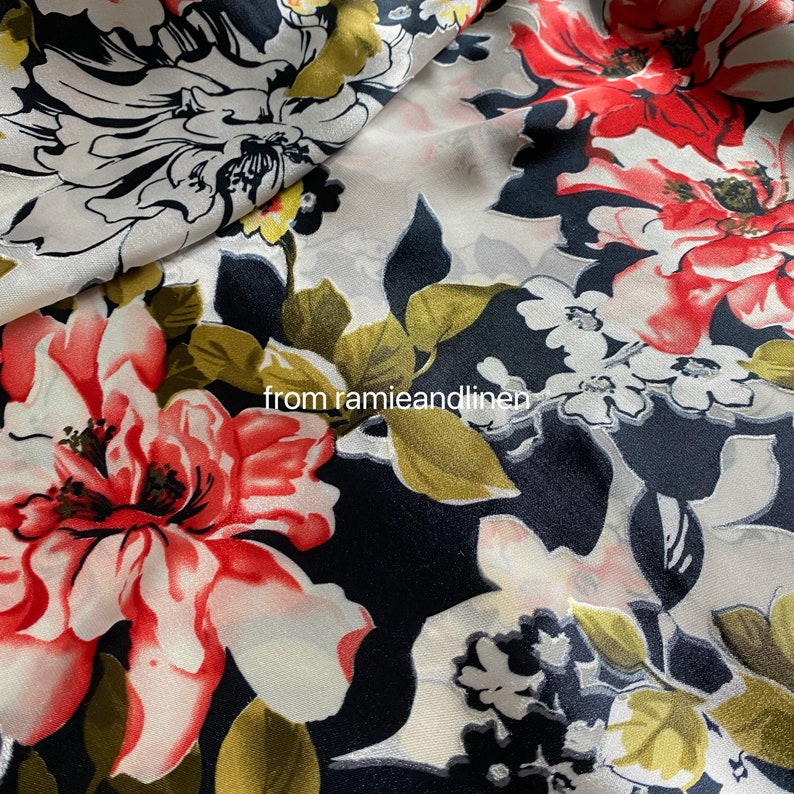 May include: Black fabric with a floral print featuring large red, white, and pink flowers with green leaves. The fabric has a subtle sheen.