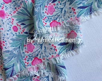 Puede incluir: Primer plano de una tela floral con fondo blanco. La tela presenta un estampado de flores rosas, hojas turquesas y detalles azules. Los bordes están deshilachados y se ve el texto "by ramieandlinen".