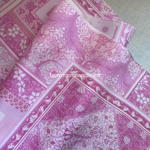May include: Pink floral fabric with a repeating pattern of stylized flowers and leaves. The fabric is folded in half, showing the pattern on both sides. The text "from ramieandlinen" is visible in the center of the image.