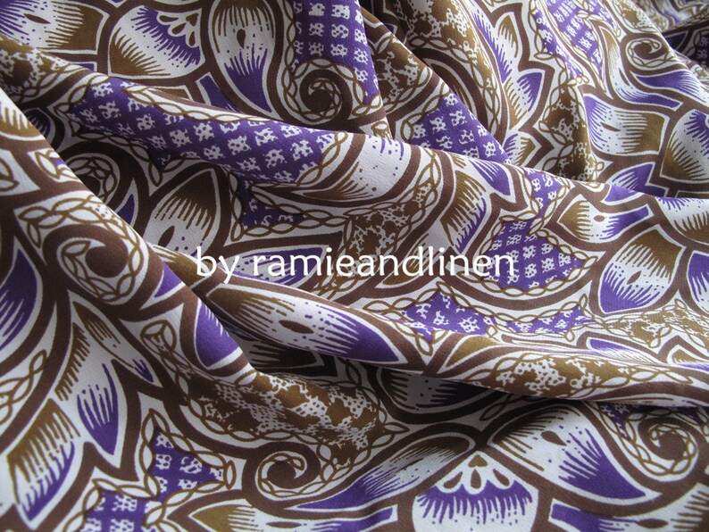 May include: Purple and brown patterned fabric with a paisley design. The fabric is woven and has a soft, drapey texture.