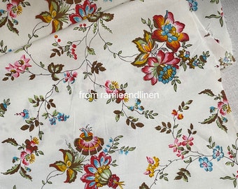 May include: White fabric with a floral pattern featuring red, pink, blue, and yellow flowers. The flowers are arranged in a repeating pattern on a white background.