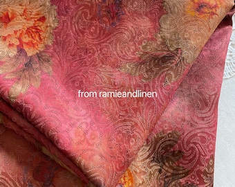 May include: Red fabric with a brown and gold paisley pattern. The fabric has a subtle sheen and a textured surface.