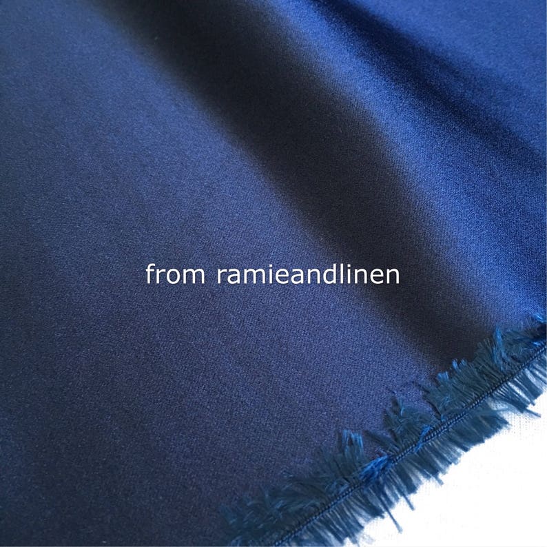 May include: Close-up of a dark blue fabric with a fringed edge. The fabric has a smooth, silky texture. The text "from ramieandlinen" is visible in the center of the image.
