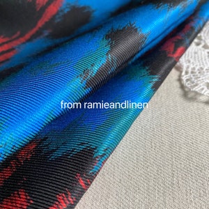 May include: Close-up of a blue, red, and black patterned fabric with a textured surface. The fabric is folded over and the text "from ramieandlinen" is visible.