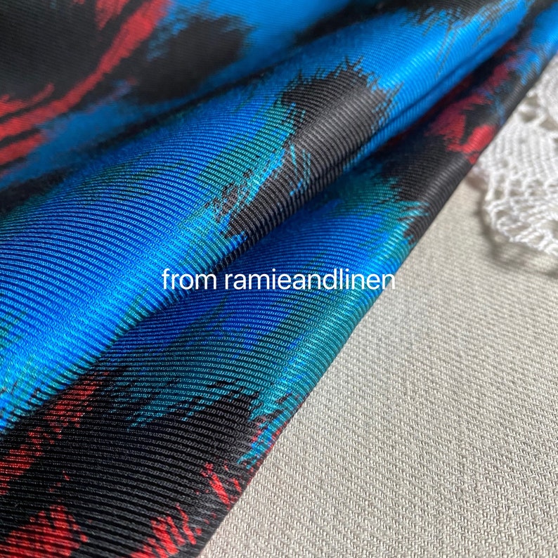 May include: Close-up of a blue, red, and black patterned fabric with a textured surface. The fabric is folded over and the text "from ramieandlinen" is visible.