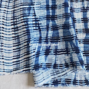 May include: Blue and white striped fabric with a textured, woven look. The fabric has a subtle tie-dye pattern and is folded in half. The text "from ramieandlinen" is visible in the lower centre of the image.
