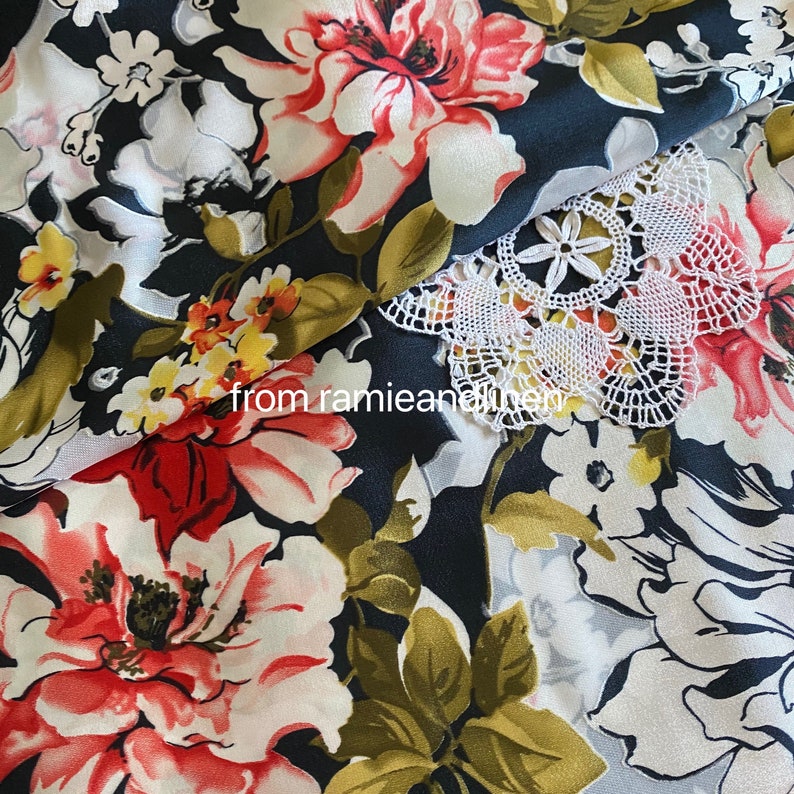May include: Black fabric with a floral pattern featuring large red, white, and pink flowers. A white crocheted lace overlay is visible in the top right corner. The text "from ramieandlinen" is visible in the bottom left corner.