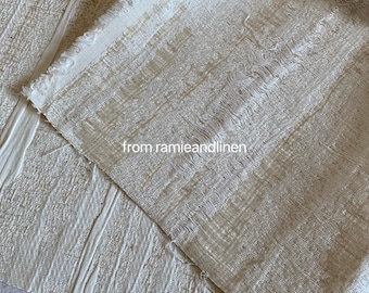 Puede incluir: Dos piezas de tela de color blanco roto con textura tejida. La tela de arriba tiene una textura ligeramente más rugosa y está etiquetada con "from ramieandlinen".