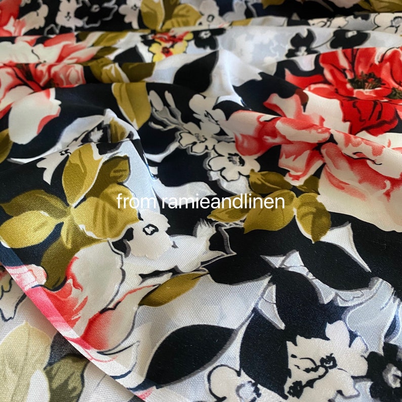 May include: White fabric with a black, red, and gold floral print. The fabric is sheer and has a soft, flowing texture.  The flowers are large and bold, and the print is very detailed.  The fabric is perfect for making dresses, skirts, blouses, and other garments.