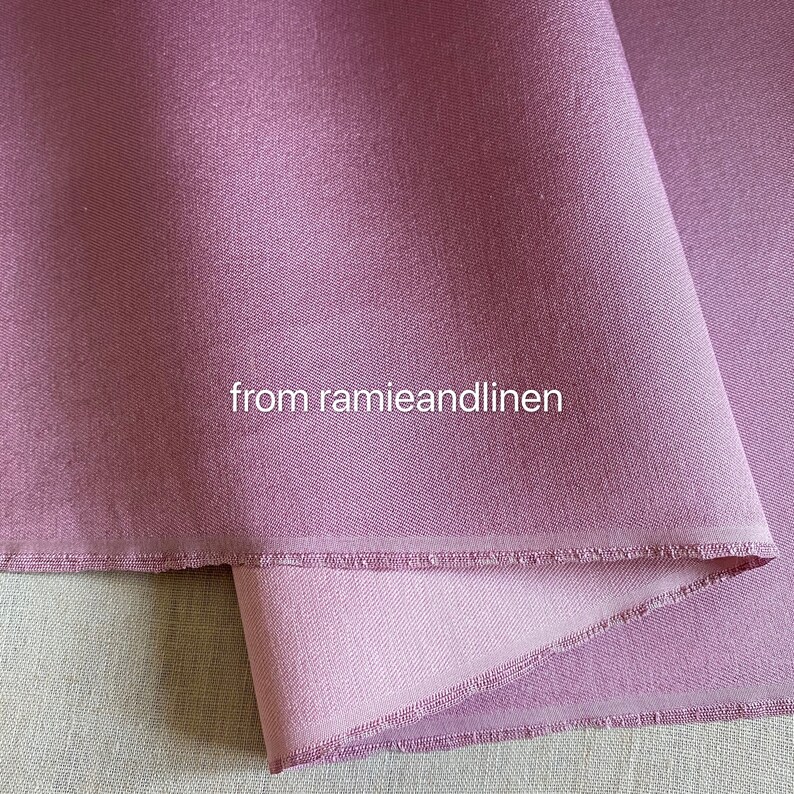 May include: A close-up of a soft, mauve-colored fabric with a subtle texture. The fabric is folded over, revealing a lighter shade of mauve underneath. The text "from ramieandlinen" is visible in the center of the image.