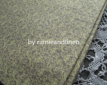 Pode incluir: Um close-up de um tecido bege com um padrão floral verde claro. O tecido tem um brilho sutil e uma textura macia. O texto "by ramieandlinen" está impresso no tecido.