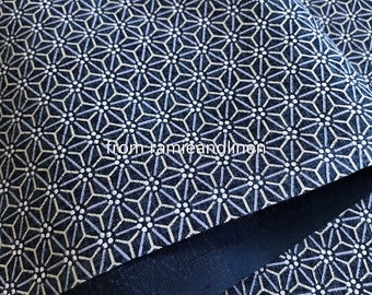 May include: A close-up of a dark blue fabric with a white and light blue geometric pattern. The fabric has a subtle texture and a soft sheen. "from ramieandlinen" is printed in white on the fabric.