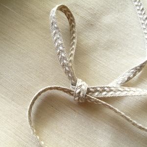 May include: A beige ribbon with a white dotted pattern. The ribbon is tied in a knot and the ends are loose.