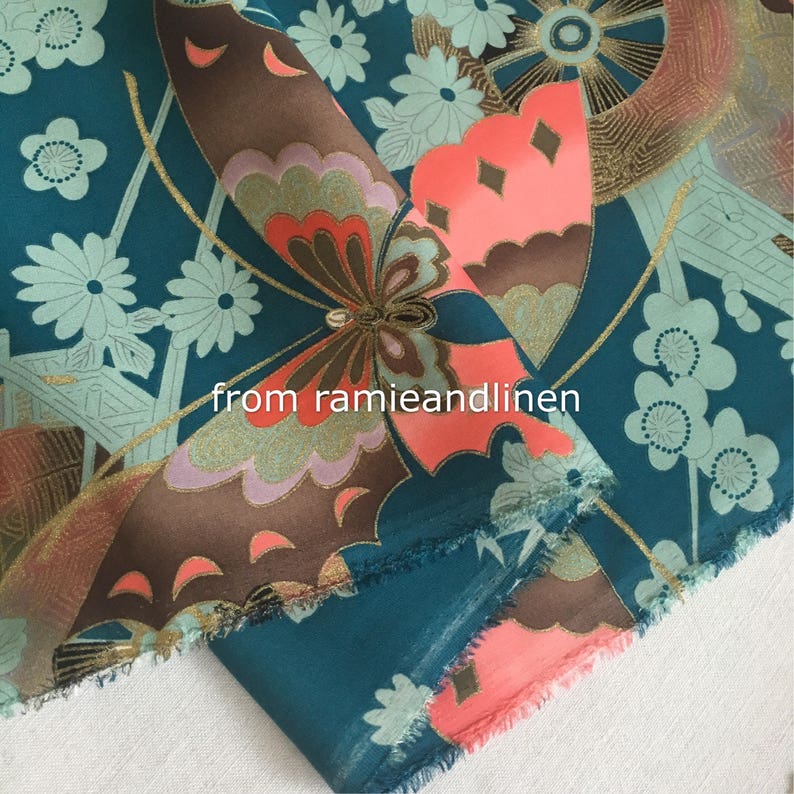 K&ouml;nnte beinhalten: Tealfarbener Stoff mit einem goldenen und braunen Schmetterlingsdruck. Der Stoff hat ein wei&szlig;es und gr&uuml;nes Blumenmuster und den Text "from ramieandlinen".