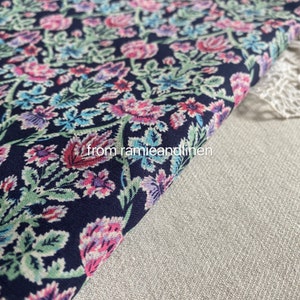 May include: A close-up of a dark blue fabric with a floral pattern in shades of pink, green, and blue. The fabric is folded over and the text "from ramieandlinen" is visible in the lower right corner.