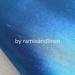 May include: Close-up of a deep blue fabric with a subtle sheen. The fabric is smooth and has a fine weave. The text "by ramieandlinen" is visible in the lower center of the image.